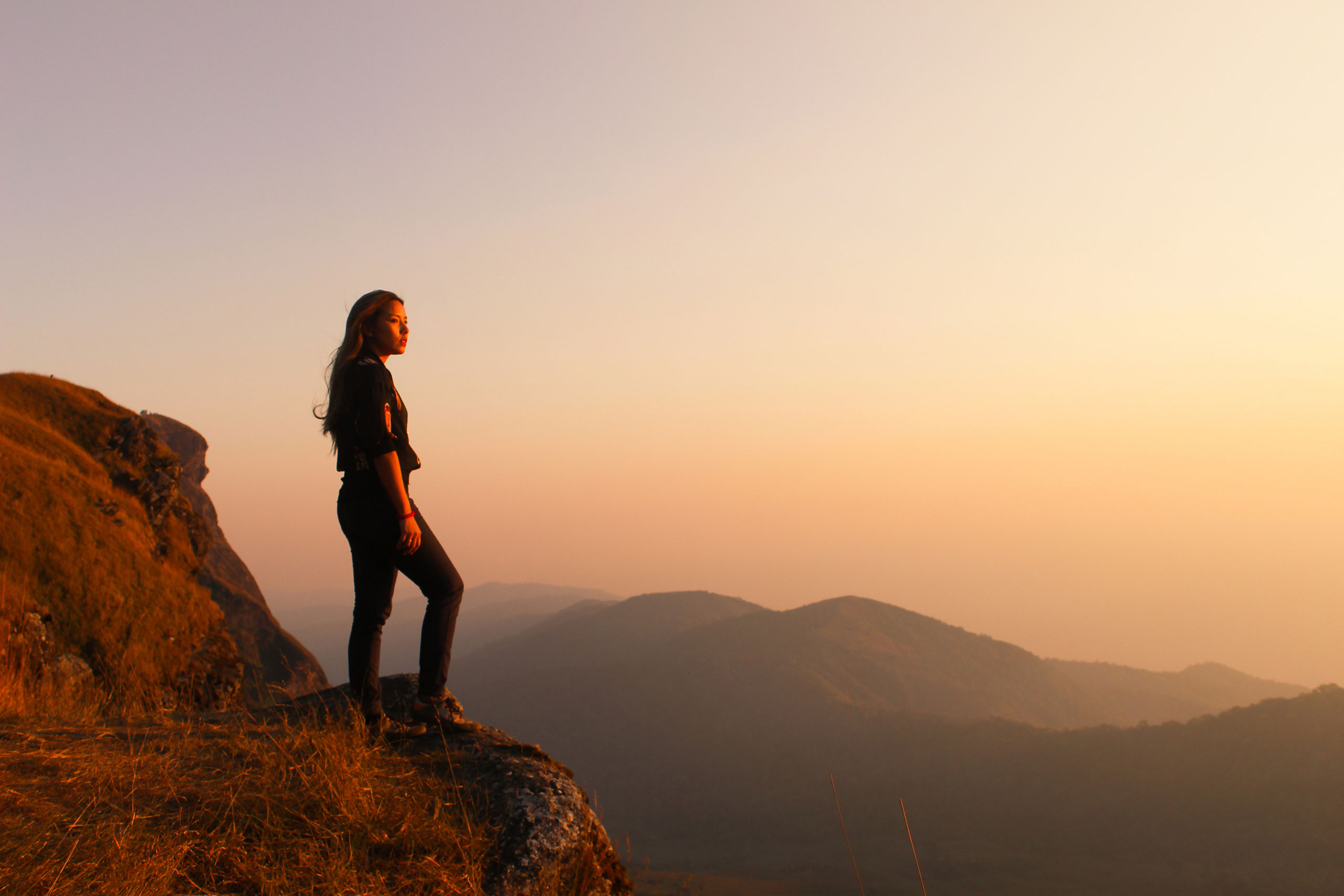 Person standing on a mountain looking at sunset